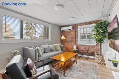 Bright living room with exposed brick, large windows, and cozy seating