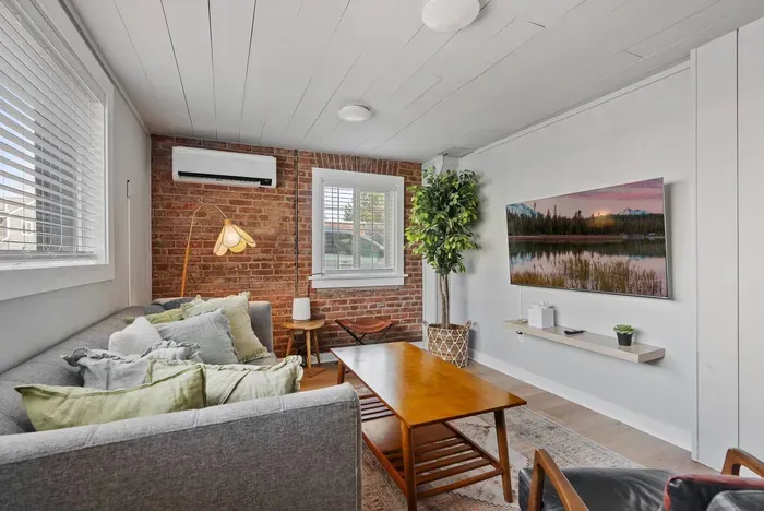 Cozy brick-accent living room with TV, natural light, and stylish decor