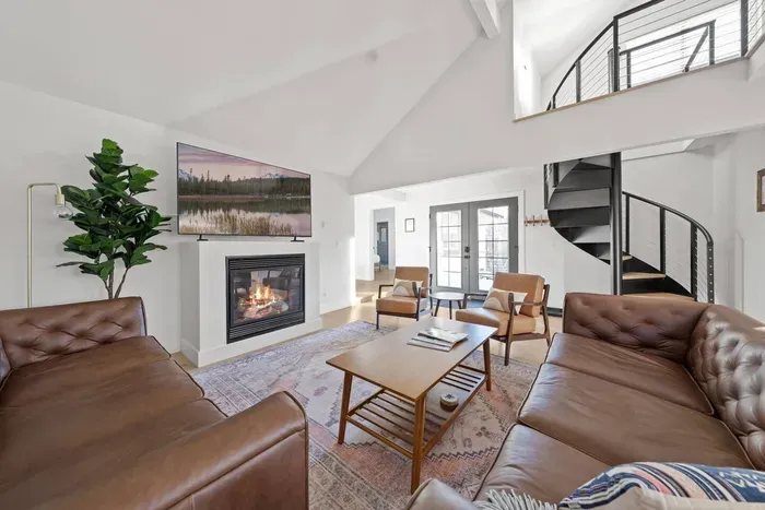 Bright vaulted living room with fireplace, loft, and stylish seating