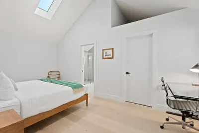 Bright vaulted bedroom with skylight, workspace, and en suite access