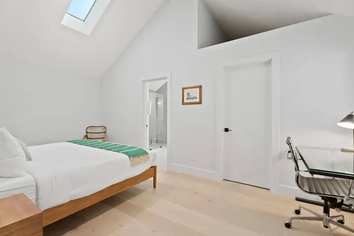 Bright vaulted bedroom with skylight, workspace, and en suite access