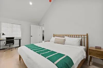 Bright vaulted bedroom with workspace and crisp, hotel-style bedding