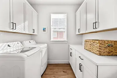 Bright laundry room with full-size washer/dryer and ample storage