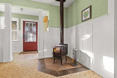 Cozy entry with wood stove, wainscoting, and red door charm