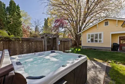 Private backyard hot tub oasis with patio, lawn, and mature trees