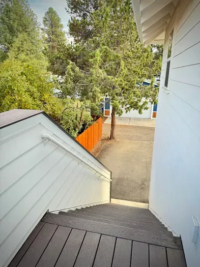 Private exterior entry with easy parking under tall pines and fencing