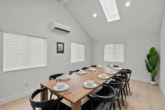 Bright vaulted dining room with skylight and seating for a group