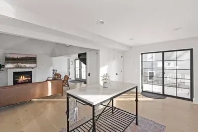 Bright open living space with fireplace, marble island, and balcony access