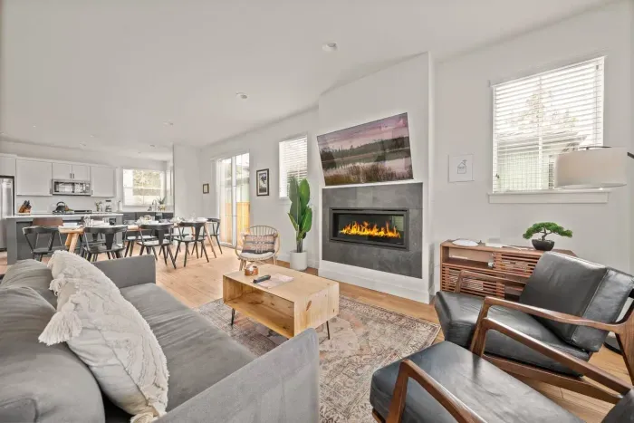 Bright open-concept living space with fireplace, dining area, and modern kitchen