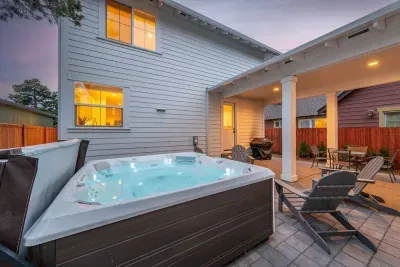 Private backyard hot tub with covered patio, grill, and cozy evening ambiance
