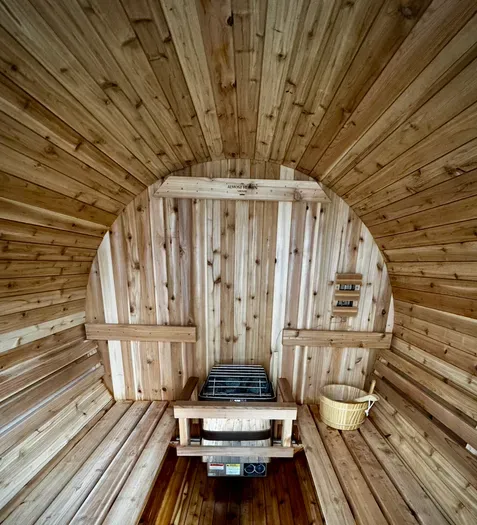Cozy cedar barrel sauna with heater, benches, and spa essentials.