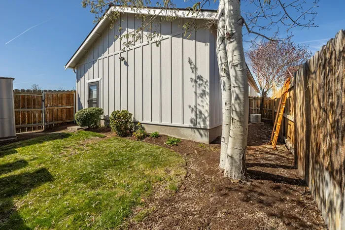 Private fenced side yard with lawn, trees, and tidy landscaping