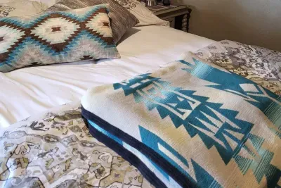 The second bedroom has a queen-size bed with a bathroom across the hall with stall shower. The room has a wall-mounted Smart TV, extra HDMI connection, and access to a charming balcony with a table and chairs for four.