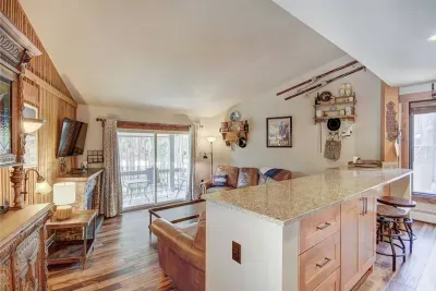 View from the entry into the beautiful living room with mountain antiques. Galley kitchen bar seats 6 on both sides.