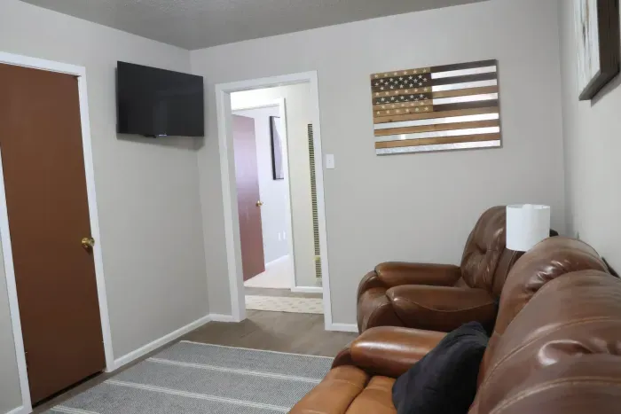 Living room with wall-mounted TV and leather recliners.