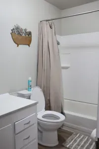 Clean bathroom with shower-tub combo, storage cabinet, and linens provided.
