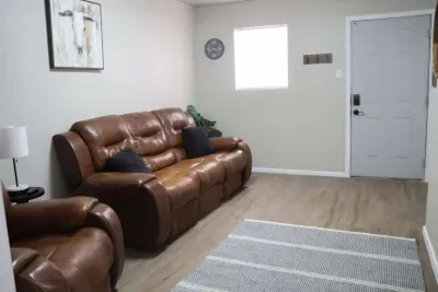 Living room with leather sofa, natural light, and coat hooks by entry door.