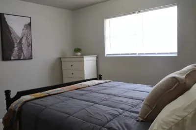 Queen bed with dresser and natural light.