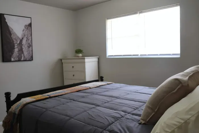 Queen bed with dresser and natural light.