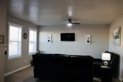 Bright living room with ceiling fan, natural light, and comfortable seating for relaxing.