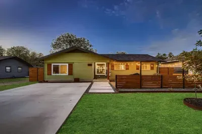 Admire the front exterior in the evening, where warm lights highlight the vibrant apple green color of the house. The well-manicured lawn complements the scene, with a touch of blue sky adding to the serene ambiance.