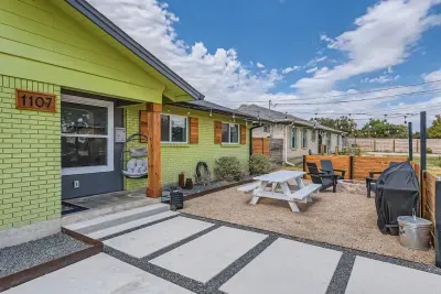 Experience the amazing outdoor space in the front, featuring a beautiful white wooden table and chairs arranged around a cozy fire pit. This charming setup creates the perfect atmosphere for relaxing and enjoying the outdoors.
