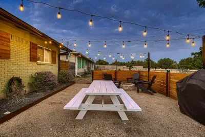 Experience the amazing outdoor space in the front, beautifully lit for a cozy ambiance. The fenced area features a rustic wooden table, perfect for dining or relaxing while enjoying the serene surroundings.