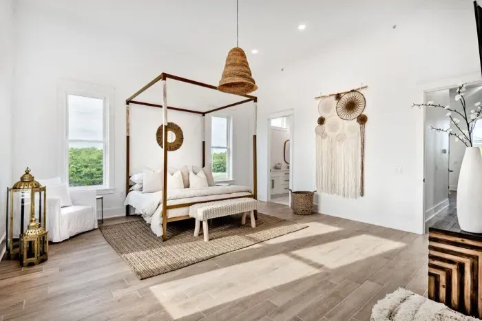 A serene and spacious bedroom featuring a cozy four-poster bed, natural textures, and soft, earthy tones.