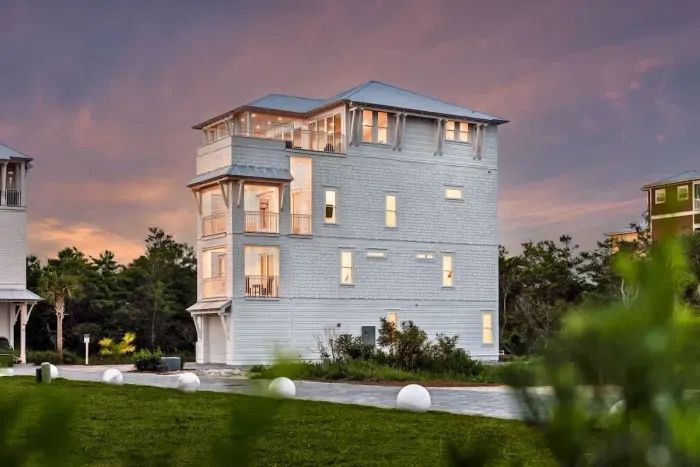 5. This multi-story home boasts a stunning modern coastal design with crisp white siding and elegant trim details.