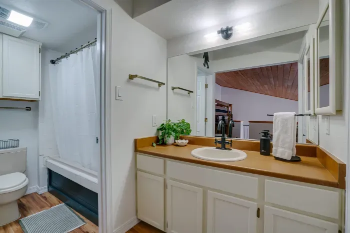 A clean, well-appointed full bathroom featuring warm wood countertops, updated fixtures, and soft lighting.