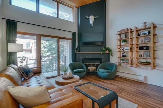 A stunning open living space featuring dramatic vaulted ceilings, designer décor, and floor-to-ceiling windows that fill the room with mountain sunlight.