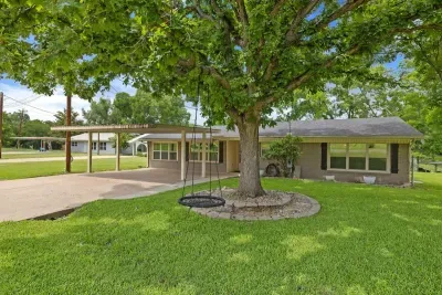 Inviting front yard with mature trees, a lovely garden, and a peaceful atmosphere.