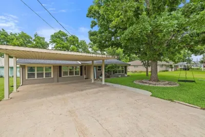 Front exterior with a neat driveway and shaded trees.