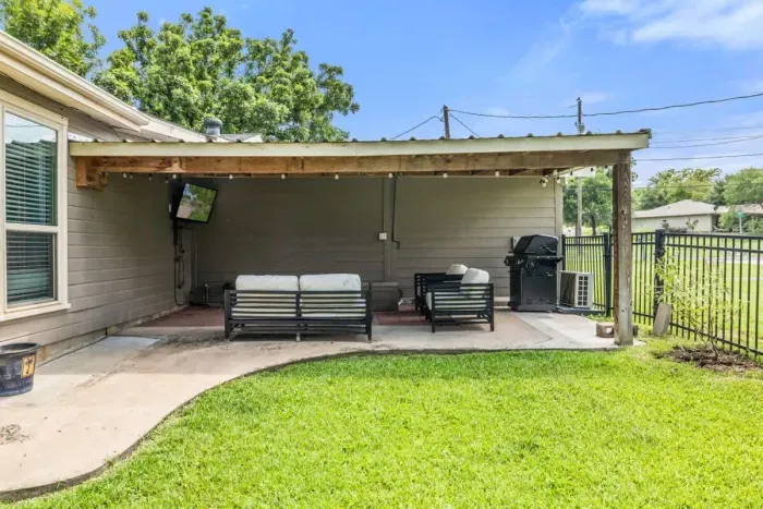 Relax under the covered patio, complete with lounge seating, outdoor TV, and grill; perfect for unwinding or entertaining in any weather.