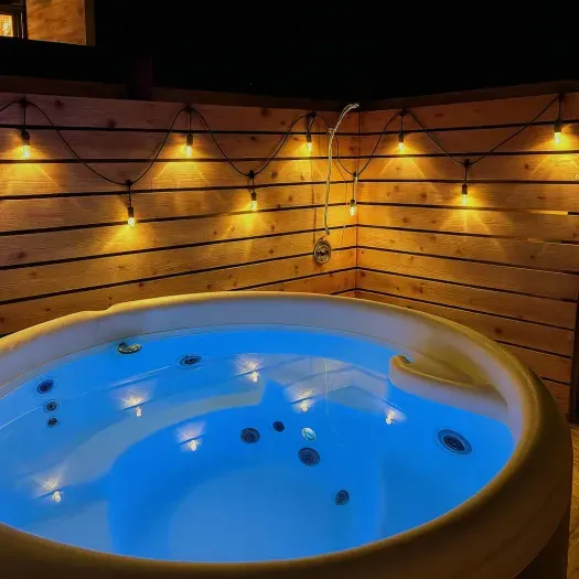 A privacy screen and lighting set the tone for a relaxing dip in the hot tub!