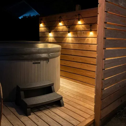 A privacy screen and lighting set the tone for a relaxing dip in the hot tub!