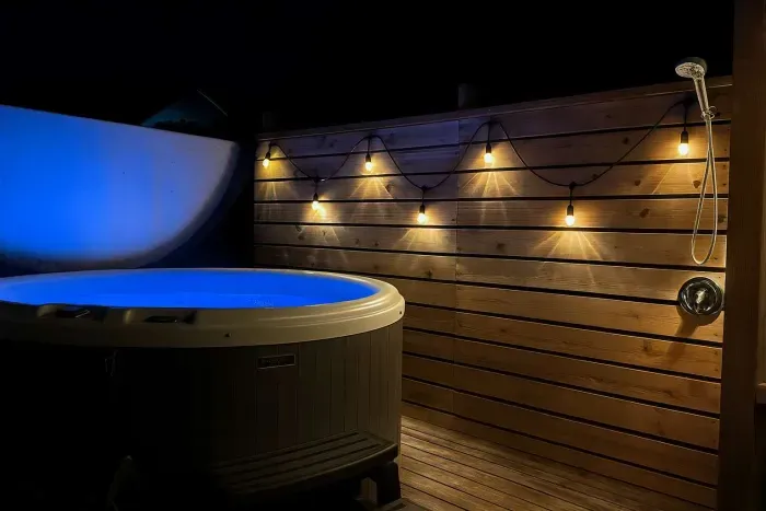 A privacy screen and lighting set the tone for a relaxing dip in the hot tub!
