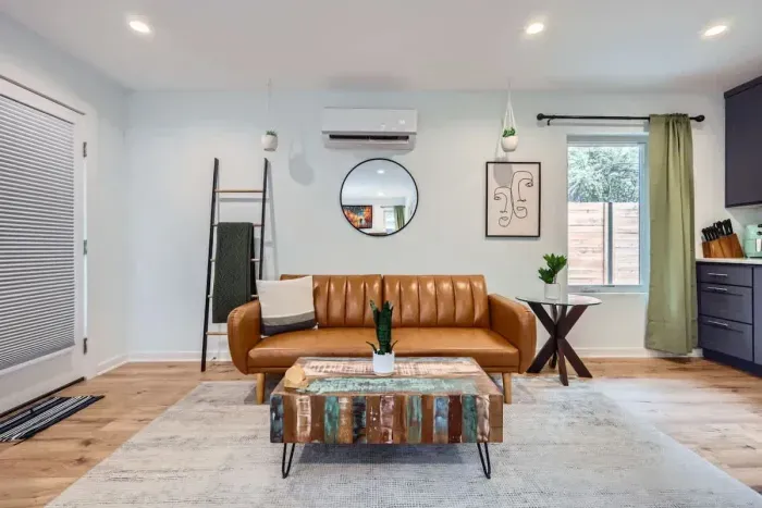 Stylish living room with mid-century leather sofa, eclectic artwork, and natural light. Cozy space to relax or enjoy conversation.