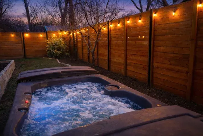 Unwind in the bubbling spa surrounded by warm lighting and privacy fencing.