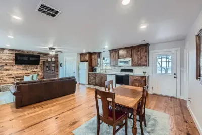 Enjoy an open-concept layout with a fully equipped kitchen, dining area, and living room accented by warm wood finishes.