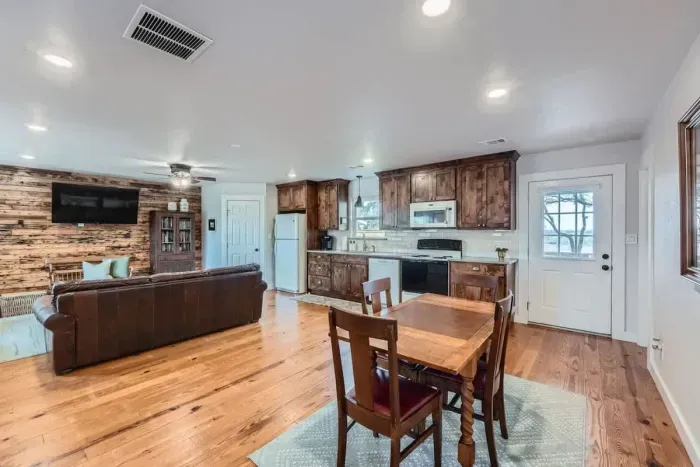 Enjoy an open-concept layout with a fully equipped kitchen, dining area, and living room accented by warm wood finishes.