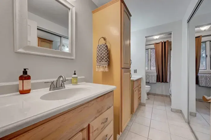 Bright guest bathroom with fresh towels, natural light, and forest-themed art.