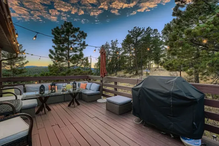 Expansive deck with grill, seating, and panoramic mountain scenery.