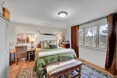 Peaceful primary bedroom with cozy bedding, scenic forest views, and warm mountain decor.