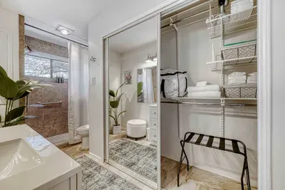 Spacious primary bathroom with walk in shower, mirrored closet, and organized storage for a seamless stay