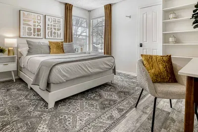 Bright corner bedroom with plush king bed, layered textures, and natural light for a calm and restful stay