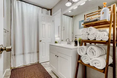 Bright bathroom with modern vanity, fresh towels, and a clean shower setup ready for your stay