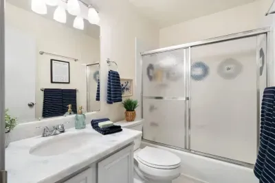 Spacious bathroom with fresh towels, vanity storage, and a shower-tub combo.