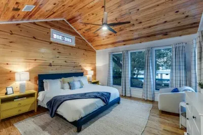 Cozy bedroom with wood-paneled walls and sliding doors to the outdoors.