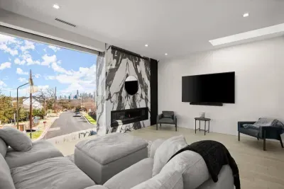 Unwind in a modern living space with floor-to-ceiling windows, fireplace, and a theater-style TV for the perfect night in